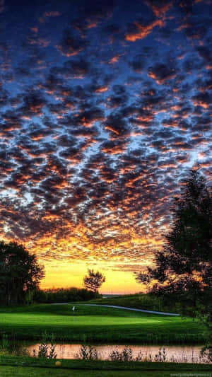 A Golf Course With A Sunset Over The Water Wallpaper