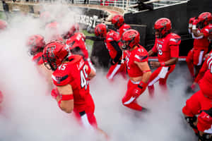 A Group Of Football Players Walking Through Smoke Wallpaper