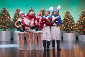 A Group Of People In Costumes On Stage With Christmas Trees Wallpaper