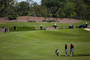 A Group Of People Playing Golf On A Green Field Wallpaper