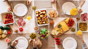 A Group Of People Sitting Around A Table With Food Wallpaper