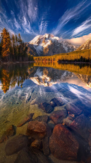 A Lake With Rocks And Mountains In The Background Wallpaper