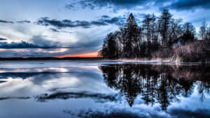 A Lake With Trees And Clouds In The Background Wallpaper