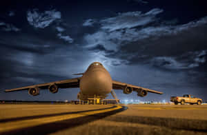 A Large Military Aircraft On The Runway At Night Wallpaper