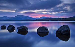 A Large Stone In The Tranquil Lake Wallpaper