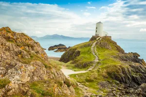 A Lighthouse On A Rocky Cliff Overlooking The Ocean Wallpaper