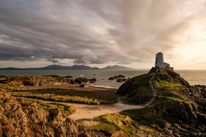 A Lighthouse Sits On Top Of A Rocky Cliff Overlooking The Ocean Wallpaper