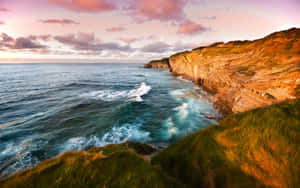 A Majestic Coastal Scene Under A Pink-clouded Sky Wallpaper