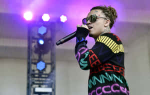 A Man In A Colorful Sweater Is Singing Into A Microphone Wallpaper