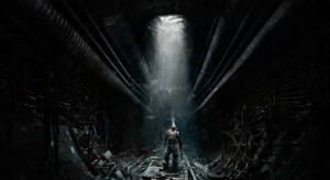 A Man Is Standing In A Dark Tunnel With A Light Shining Through Wallpaper