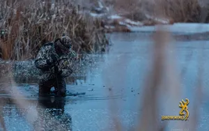 A Man Is Standing In A Pond With Reeds Wallpaper