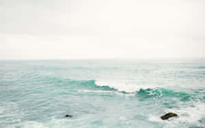 A Man Is Standing On A Rock In The Ocean Wallpaper