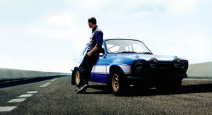 A Man Is Standing On The Side Of A Road With A Blue Car Wallpaper