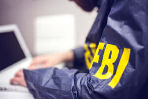 A Man Is Using A Laptop With The Word Fbi On It Wallpaper