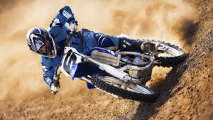 A Man Riding A Dirt Bike On A Dirt Track Wallpaper