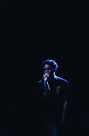 A Man Singing Into A Microphone In The Dark Wallpaper
