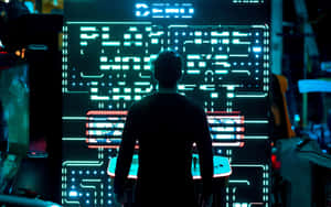 A Man Standing In Front Of A Large Electronic Game Wallpaper