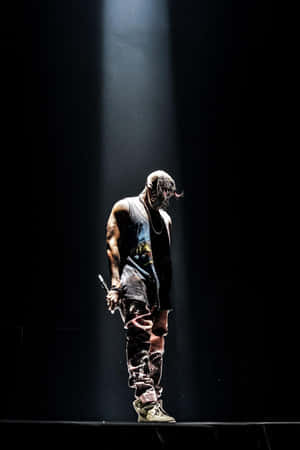 A Man Standing On A Stage With A Spotlight Wallpaper