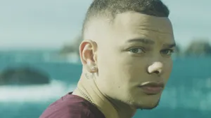 A Man With A Pierced Ear Is Looking At The Ocean Wallpaper