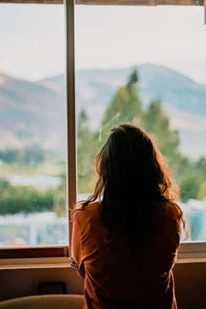 A Melancholic Moment: Young Woman Feeling Sad By The Window Wallpaper