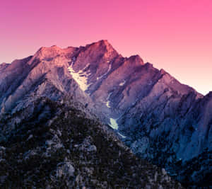 A Mountain Range With A Pink Sky And Snow Wallpaper