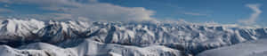 A Mountain Range With Snow Covered Mountains And Clouds Wallpaper