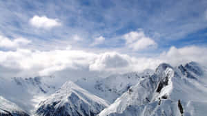 A Mountain Range With Snow Covered Mountains And Clouds Wallpaper