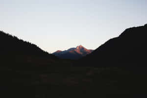 A Peaceful Vista Of A Minimalist Mountain Rises Into A Beautiful Blue Sky Wallpaper