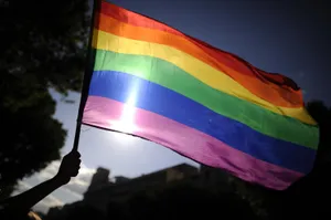 A Person Is Holding A Rainbow Flag In Front Of A Building Wallpaper