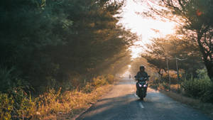 A Person Riding A Motorcycle Down A Road Wallpaper