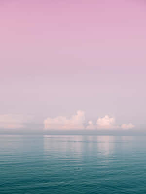 A Pink And Blue Sky With Clouds Over The Ocean Wallpaper