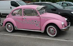 A Pink Volkswagen Beetle Parked In A Parking Lot Wallpaper