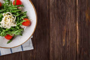 A Plate Of Salad With Tomatoes And Greens Wallpaper