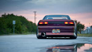 A Purple Car Is Parked On A Road At Sunset Wallpaper