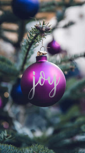 A Purple Christmas Ornament With The Word Joy Hanging On It Wallpaper