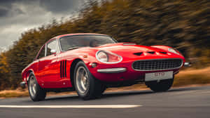 A Red Sports Car Driving Down A Road Wallpaper