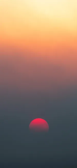 A Red Sun Rising Over A Fog Filled Sky Wallpaper