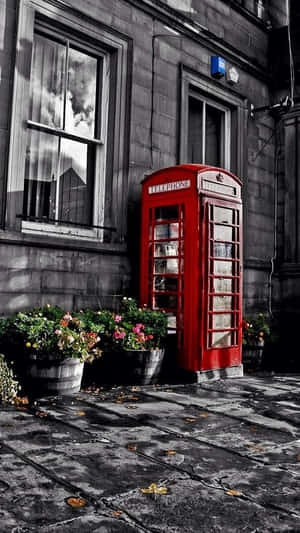 A Red Telephone Booth In Front Of A Building Wallpaper