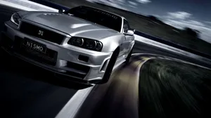 A Silver Sports Car Driving Down A Track Wallpaper