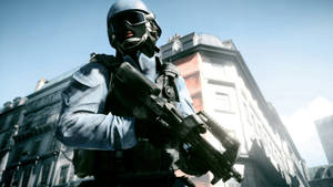 A Soldier In A Helmet And A Gun Is Standing In A City Wallpaper