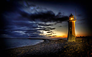 A Solitary Lighthouse Guiding The Way Wallpaper