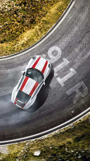 A Sports Car Driving Down A Winding Road Wallpaper