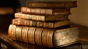 A Stack Of Old Books On A Table Wallpaper