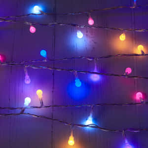 A String Of Multi Colored Lights On A Wooden Surface Wallpaper