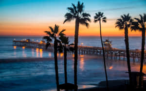 A Sunrise Glows Atop The Malibu Beach Shoreline Wallpaper