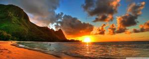 A Sunset Over A Beach With Mountains In The Background Wallpaper