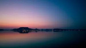 A Sunset Over A Lake With Mountains In The Background Wallpaper