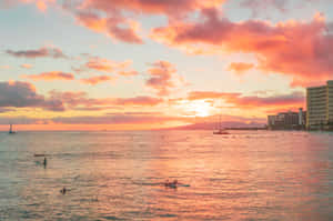 A Sunset Over The Ocean With People In The Water Wallpaper