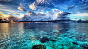 A Vast And Majestic Blue Ocean With Majestic Orange-tinged Clouds In The Sky. Wallpaper