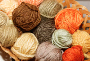 A Vibrant Basketful Of Multicolored Knitting Yarns Wallpaper